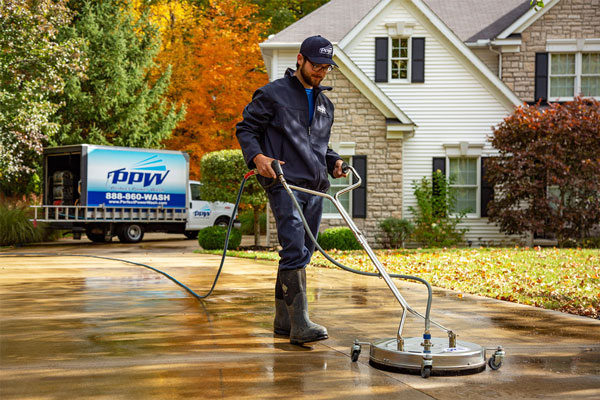 Image of a Hydro Savage Pressure Washing technician cleaning concrete with a surface cleaner