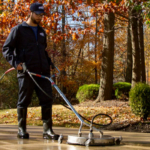 Hydro Savage Pressure Washing technician surface cleaning a concrete driveway during the fall