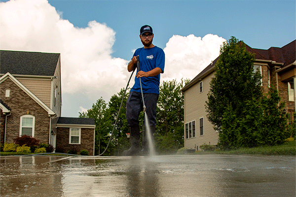 Hydro Savage Pressure Washing employee power washing concrete