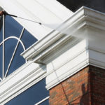 Power washing technician on a commercial lift using safe pressure to wash a municipal building