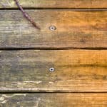 Dirty wooden deck floor next to freshly cleaned wooden deck floor to show results of power washing