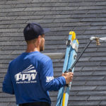 Hydro Savage Pressure Washing technician performing a soft wash roof treatment to remove roof streaks caused by Gloeocapsa Magma.