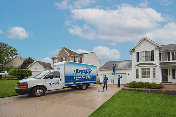Hydro Savage Pressure Washing technicians cleaning a roof, driveway, and house