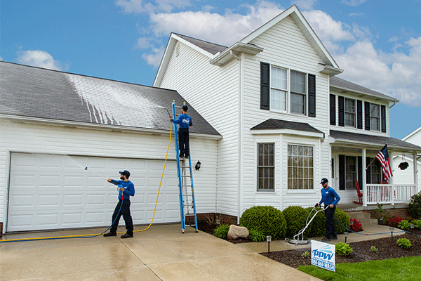 Hydro Savage Pressure Washing technicians cleaning a roof, driveway, and house
