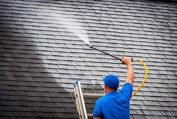 Power washing technician treating a roof with extremely low pressure