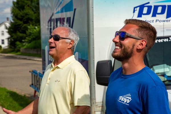 Smiling power washing technician next to satisfied customer discussing the service that was performed